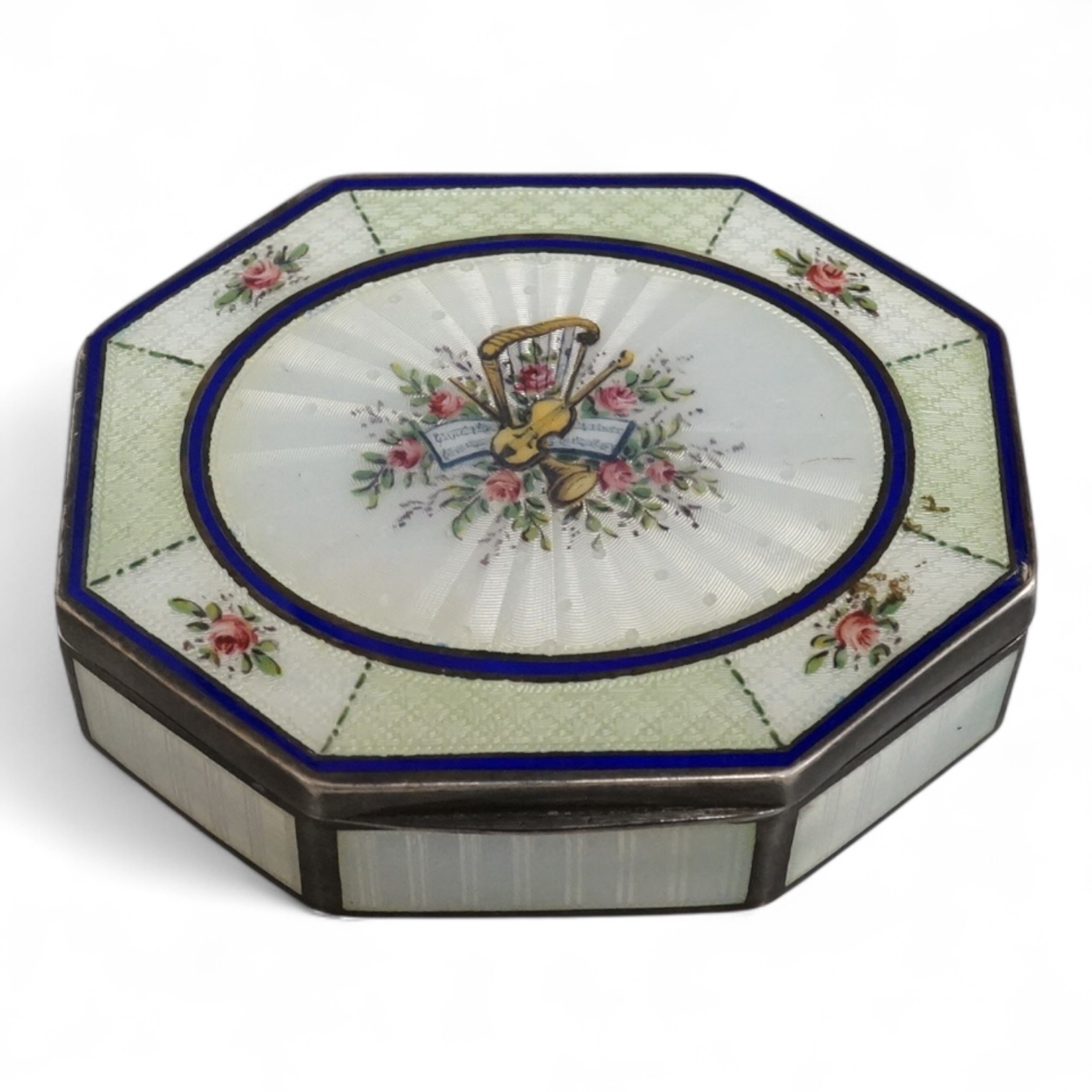 An Edwardian silver and guilloche enamel octagonal box with hinged cover, import marks for Erich Kellerman, London, 1909, decorated with flowers and musical instruments, 77mm.